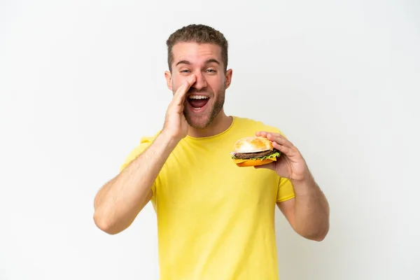 Młody Biały Mężczyzna Trzyma Hamburgera Odizolowany Białym Tle Krzycząc Usta — Zdjęcie stockowe