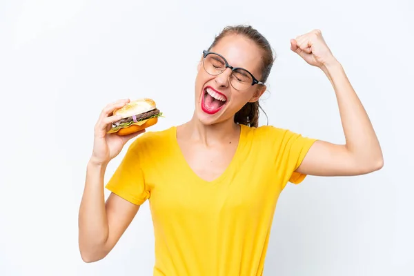 Młoda Kaukaska Kobieta Trzyma Hamburgera Białym Tle Świętując Zwycięstwo — Zdjęcie stockowe