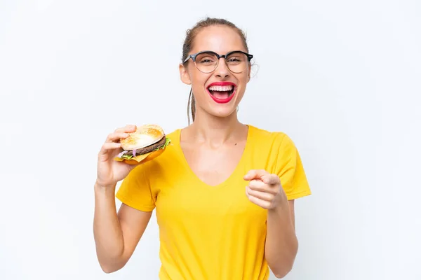 Młoda Kaukaska Kobieta Trzyma Hamburgera Izolowane Białym Tle Zaskoczony Wskazując — Zdjęcie stockowe