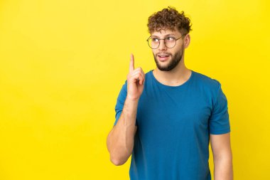 Sarı arka planda izole edilmiş genç, yakışıklı beyaz adam bir fikir düşünüyor.