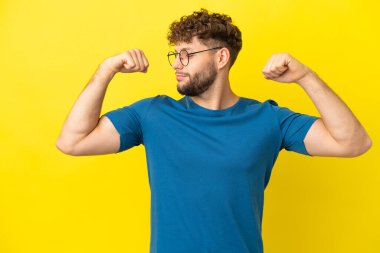 Sarı arka planda izole edilmiş yakışıklı beyaz adam güçlü bir jest yapıyor.