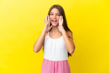 Küçük beyaz kız sarı arka planda izole edilmiş bağırıyor ve bir şeyler söylüyor.