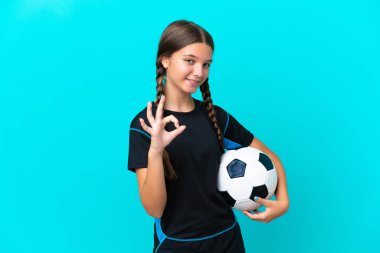 Mavi arka planda, futbol topuyla izole edilmiş küçük beyaz bir kız.