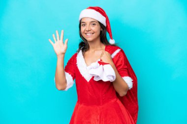 Anne Noel gibi giyinmiş genç İspanyol kadın mavi arka planda beş parmaklı bir çuval tutuyor.