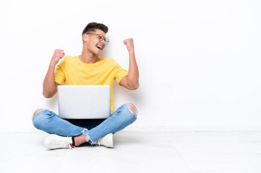 Yerde oturan genç adam beyaz arka planda tek başına zaferi kutluyor.