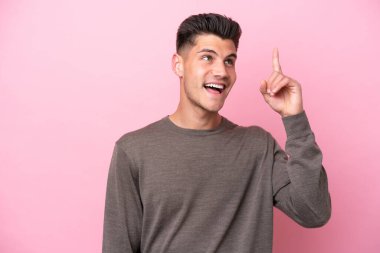 Pembe arka planda izole edilmiş genç beyaz adam çözümü bulmak için parmağını kaldırıyor.