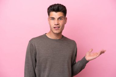 Pembe arka planda izole edilmiş genç beyaz adam şüpheli hareketler yapıyor.