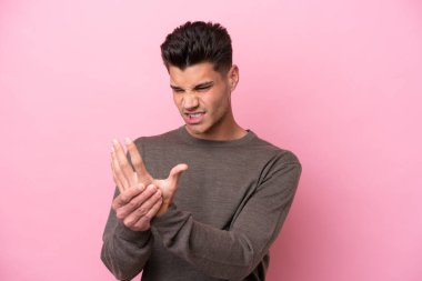 Pembe arka planda izole edilmiş beyaz bir adam ellerinde acıdan muzdarip.