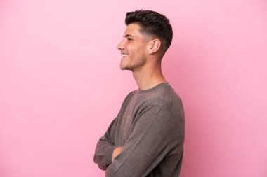 Young caucasian man isolated on pink background in lateral position