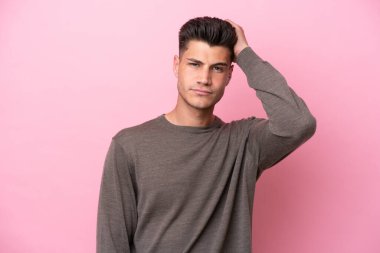 Pembe arka planda izole edilmiş genç beyaz bir adam hayal kırıklığı ifadesi ve anlamama.