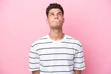 Genç beyaz adam pembe arka planda izole edilmiş ve yukarı bakıyor.