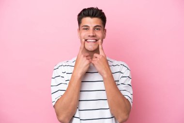 Young caucasian man isolated on pink background smiling with a happy and pleasant expression
