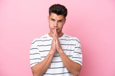 Pembe arka planda izole edilmiş genç beyaz adam avuç içlerini bir arada tutuyor. İnsan bir şey ister.