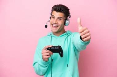 Pembe arka planda izole edilmiş bir bilgisayar oyunu kontrolörüyle oynayan yakışıklı beyaz bir adam. Çünkü iyi bir şey oldu.