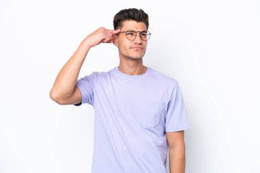 Beyaz arka planda izole edilmiş genç beyaz bir adam deliliğin hareketini yapıyor. Parmağını kafaya koyuyor.