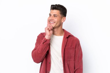 Beyaz arka planda izole edilmiş genç beyaz adam yukarı bakarken bir fikir düşünüyor.