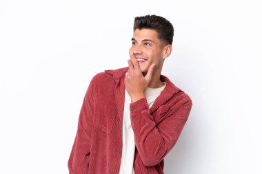 Beyaz arka planda izole edilmiş genç beyaz adam gülümserken yukarı bakıyor.