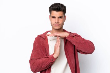 Beyaz arka planda izole edilmiş genç beyaz bir adam zaman aşımı hareketi yapıyor.