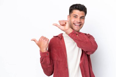 Beyaz arka planda izole edilmiş genç beyaz bir adam bir ürün sunmak için kenarı işaret ediyor.