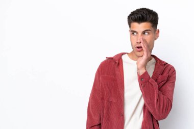Beyaz arka planda izole edilmiş genç beyaz adam yan tarafa bakarken sürpriz bir jest yapıyor.