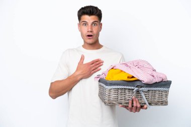 Beyaz arka planda çamaşır sepetini tutan genç beyaz adam sağa bakarken şaşırdı ve şok oldu.