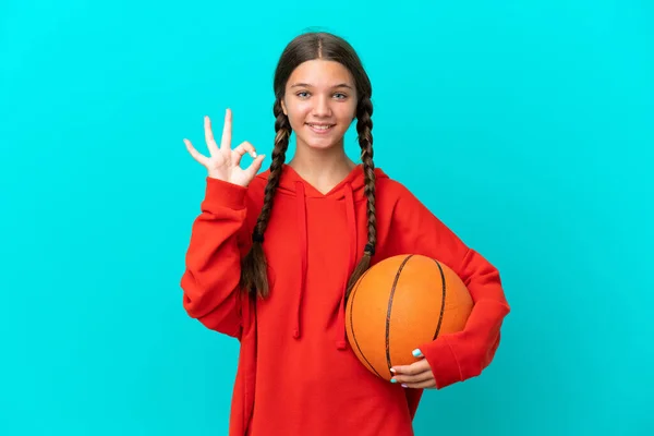 在蓝色背景下打篮球的白人小女孩用手指显示出了好的手势 — 图库照片