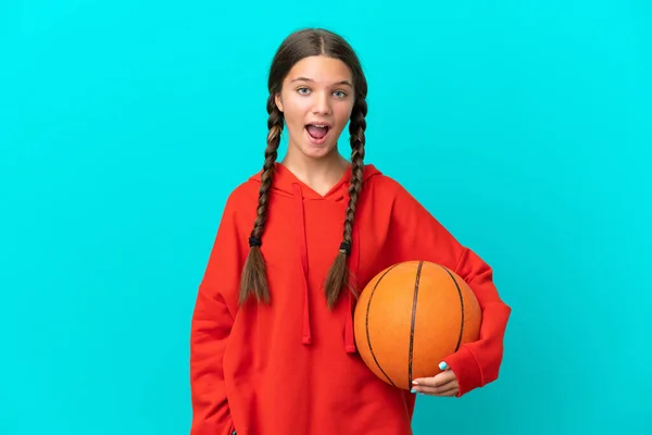 在蓝色背景下打篮球的一个高加索小女孩 脸上带着惊讶的表情 — 图库照片