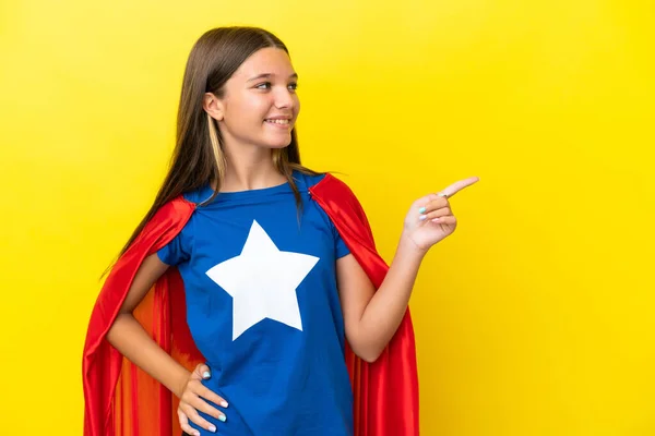 Klein Kaukasisch Superheld Meisje Geïsoleerd Gele Achtergrond Wijzend Vinger Naar — Stockfoto