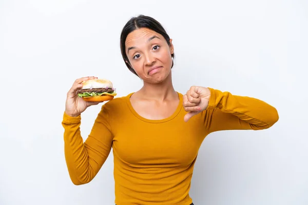Młoda Latynoska Trzymająca Hamburgera Białym Tle Negatywnym Wyrazem Twarzy — Zdjęcie stockowe