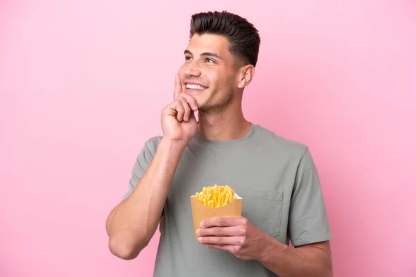 Jonge Kaukasische Man Met Gebakken Chips Geïsoleerd Roze Achtergrond Denken — Stockfoto