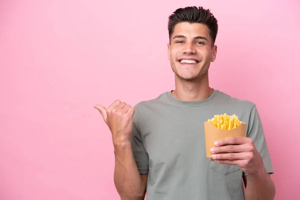 Young Caucasian Man Holding Fried Chips Isolated Pink Background Pointing — Stockfoto