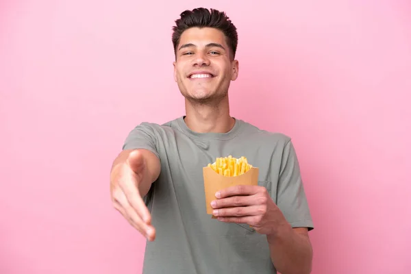 Ung Kaukasier Man Håller Stekt Chips Isolerad Rosa Bakgrund Skakar — Stockfoto