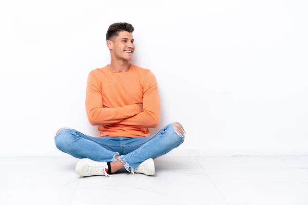 Jongeman Zit Vloer Geïsoleerd Witte Achtergrond Met Gekruiste Armen Gelukkig — Stockfoto