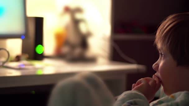 Sony fs-100 - kleiner Junge, der sich die Nase zuhält, während er Cartoons in einem dunklen Raum auf einem Computer anschaut. — Stockvideo
