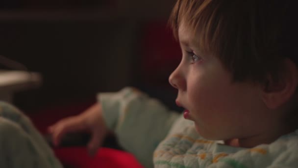 Niño viendo dibujos animados en una habitación oscura en un ordenador — Vídeo de stock