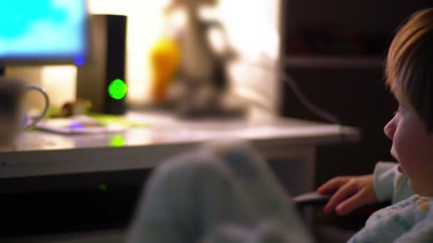 Young boy watching cartoons in a dark room on a computer — Stock Video