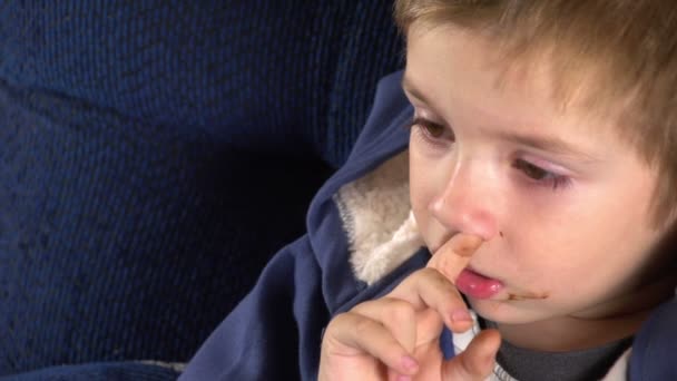 Sony FS-100 - Jeune garçon se piquant le nez en regardant la télévision — Video