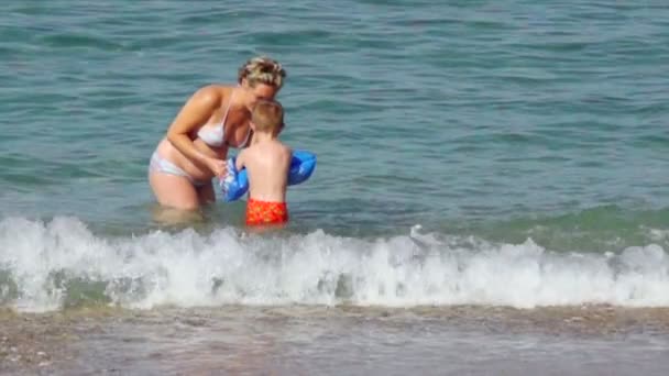 Mulheres e meninos na praia e no mar — Vídeo de Stock