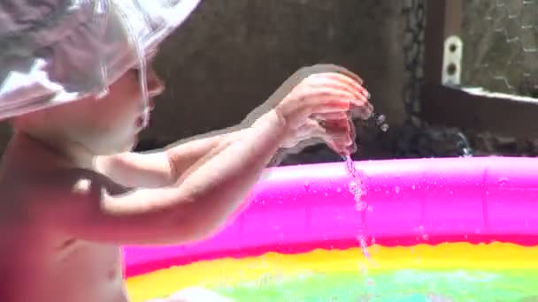 Little girl playing in the pool. Splashing and hitting the water — Stock Video