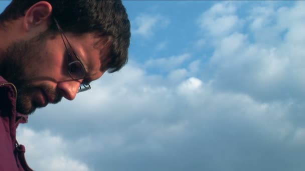 Молодий серйозний чоловік проти блакитного неба — стокове відео