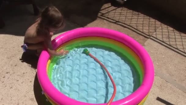 Little girl playing in the pool. Splashing and hitting the water — Stock Video