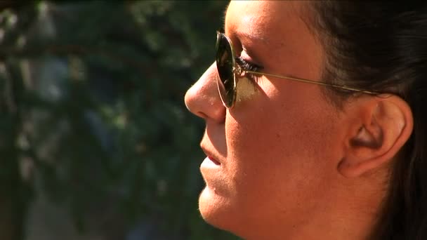 Молодая девушка среднего возраста в солнечных очках говорит . — стоковое видео