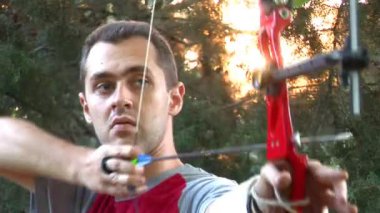 Young man shooting with bow and arrows (logos removed)