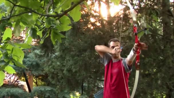 Молодий чоловік стріляє луком і стрілами — стокове відео