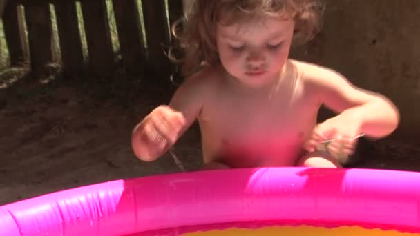 Little girl playing in the pool. Splashing and hitting the water — Stock Video