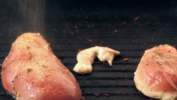 Приправлять сырые куриные филе и жарить их. — стоковое видео