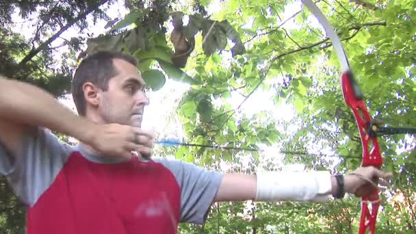 Молодой человек практикующий стрельбу из лука на природе — стоковое видео