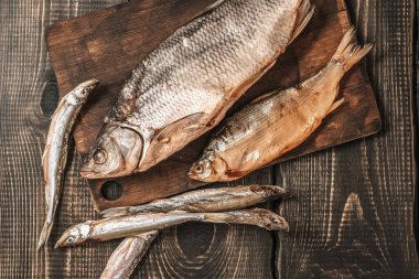 Koyu ahşap bir masada kurutulmuş balık, bira atıştırmalıkları..