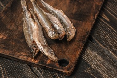 Koyu ahşap bir masada kurutulmuş balık, bira atıştırmalıkları..