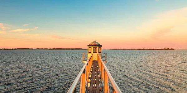 Friesland 'da Hollanda milli parkında günbatımı. Önünde antik bir deniz feneri var.